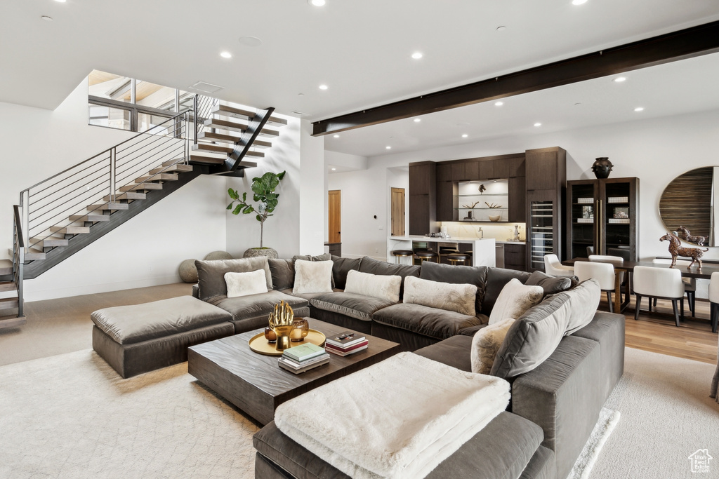 Living area featuring recessed lighting, light wood finished floors, beamed ceiling, and stairs