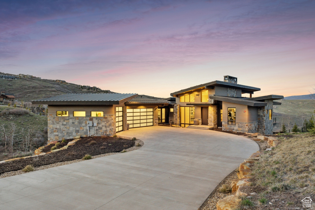 View of front of home with driveway, an attached garage, and stone siding
