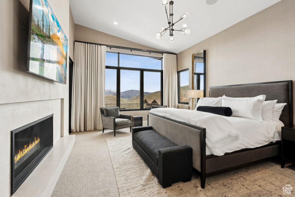 Bedroom featuring a chandelier, a warm lit fireplace, vaulted ceiling, and carpet floors