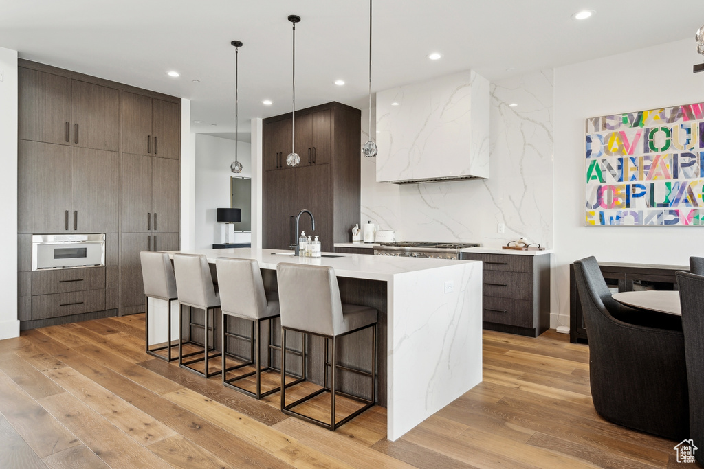 Kitchen featuring white oven, light wood-style flooring, a breakfast bar area, a sink, and modern cabinets