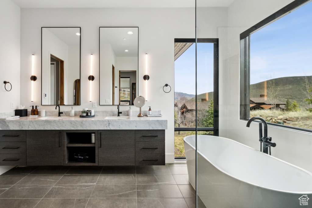 Bathroom with double vanity, a mountain view, a soaking tub, and a sink