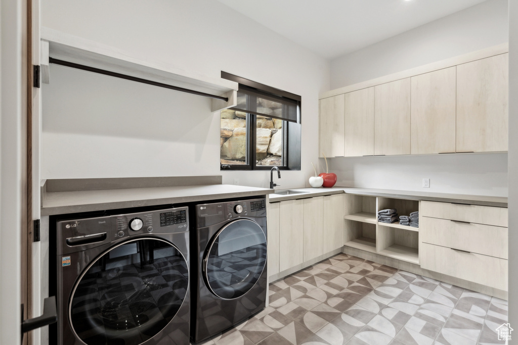 Washroom featuring light floors, washer and dryer, cabinet space, and a sink