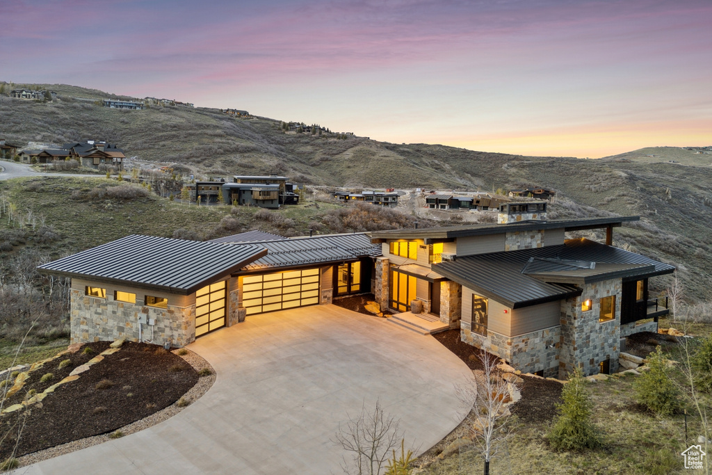 Prairie-style house with a standing seam roof, an attached garage, and stone siding
