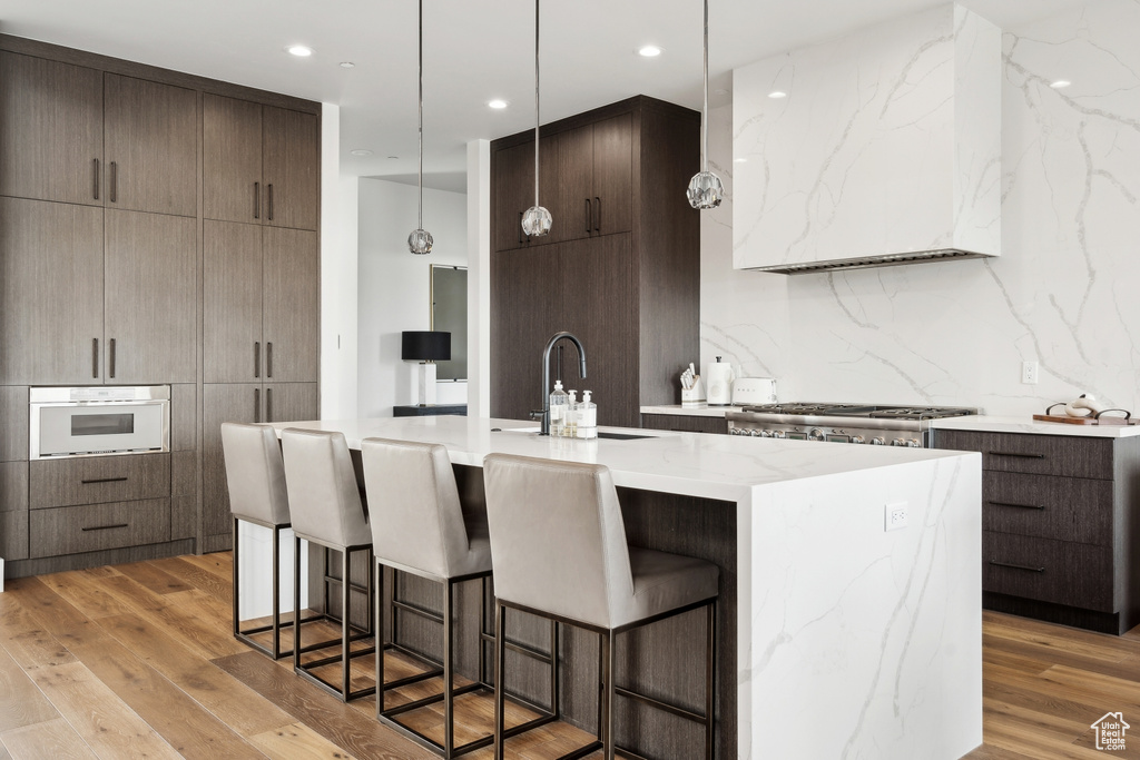Kitchen featuring a sink, modern cabinets, light wood-style floors, oven, and a breakfast bar area