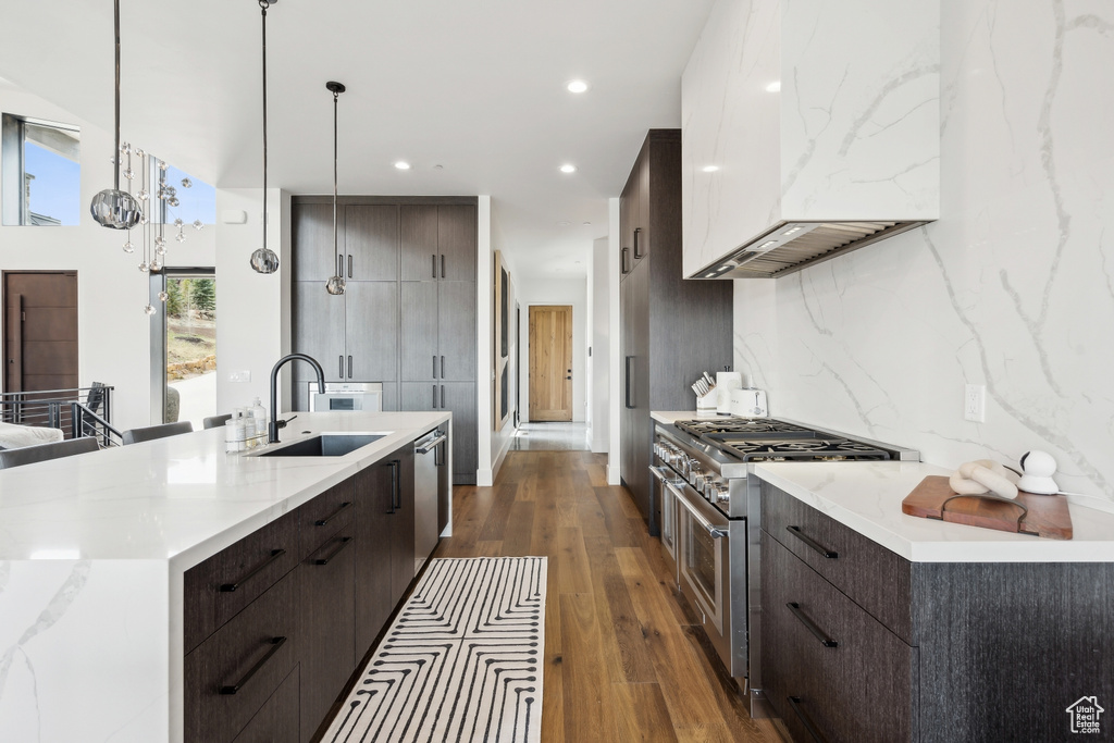 Kitchen with modern cabinets, a sink, stainless steel appliances, custom range hood, and dark brown cabinetry