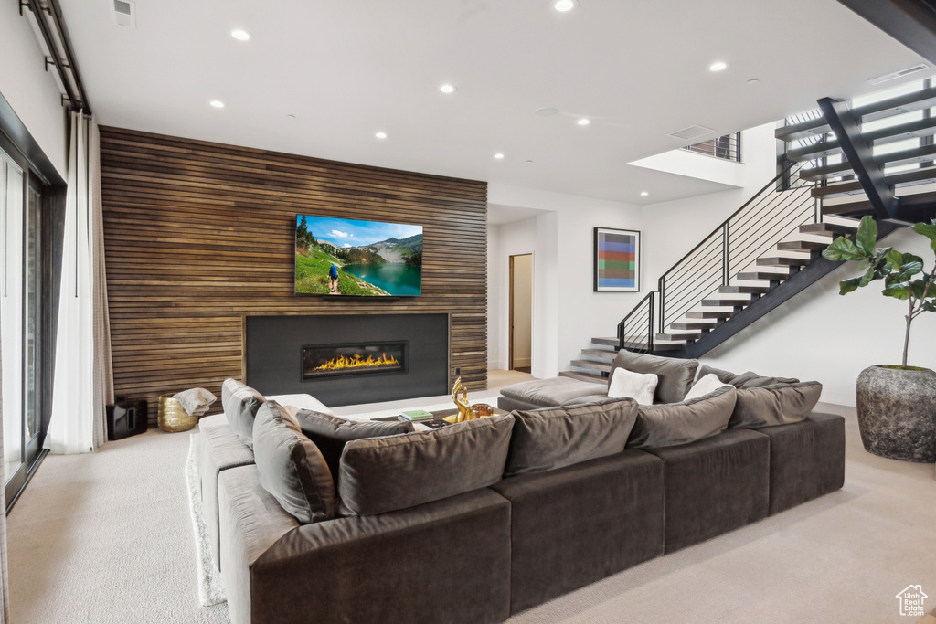 Living room featuring stairway, a glass covered fireplace, recessed lighting, and carpet