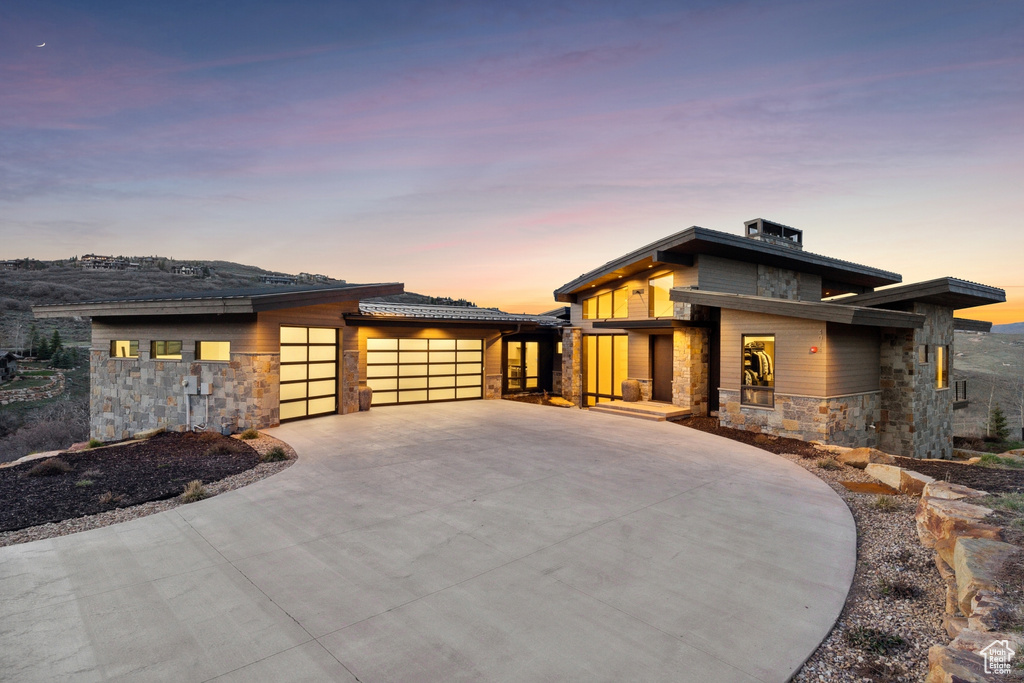 Prairie-style home with driveway, a garage, and stone siding