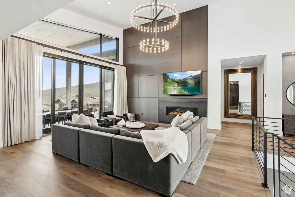 Living room with an inviting chandelier, a towering ceiling, and light wood-type flooring