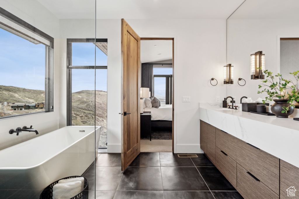 Ensuite bathroom featuring vanity, ensuite bath, tile patterned flooring, and a freestanding bath