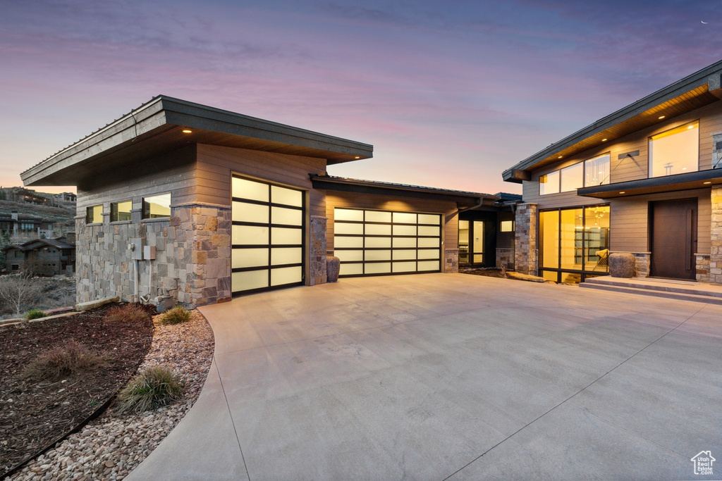 View of side of property featuring driveway, stone siding, and an attached garage