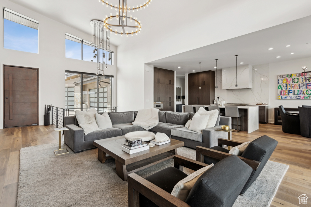 Living room with recessed lighting, a notable chandelier, and light wood-style floors