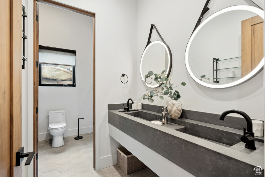 Bathroom with vanity, toilet, tile patterned flooring, and baseboards
