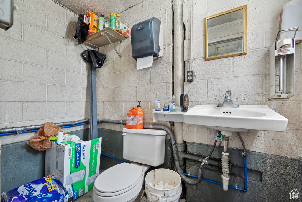 Bathroom featuring toilet, a sink, and concrete block wall