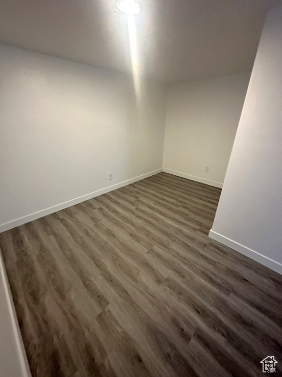 Spare room featuring baseboards and dark wood-type flooring