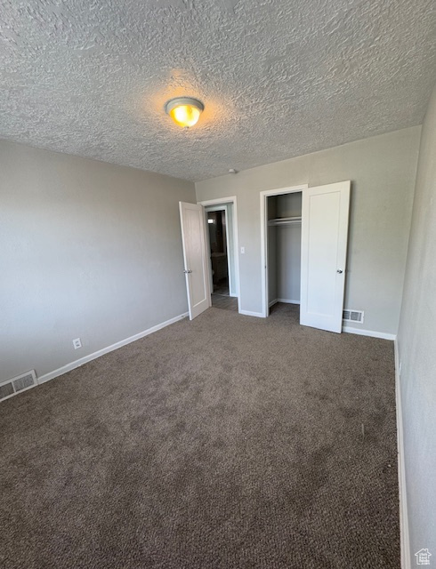 Unfurnished bedroom with visible vents, a closet, baseboards, a textured ceiling, and carpet flooring