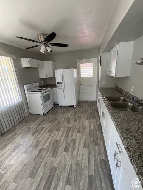 Kitchen with ceiling fan, a sink, white appliances, and a textured ceiling