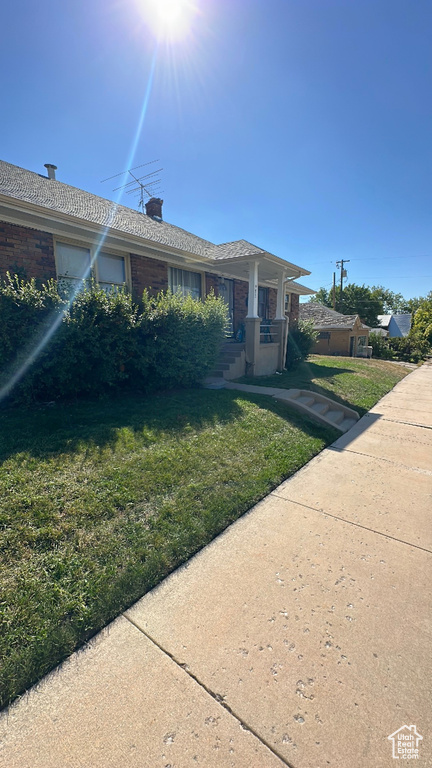 Single story home with a chimney, brick siding, and a front yard