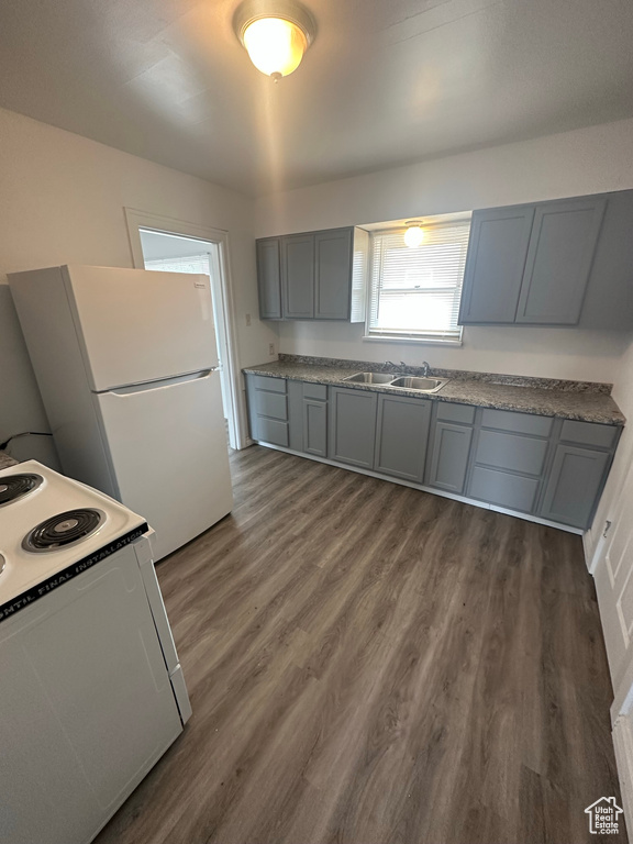 Kitchen with white appliances, a sink, dark wood-style floors, and gray cabinets