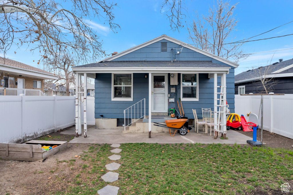 Rear view of house featuring a yard, a patio area, a shingled roof, and a fenced backyard