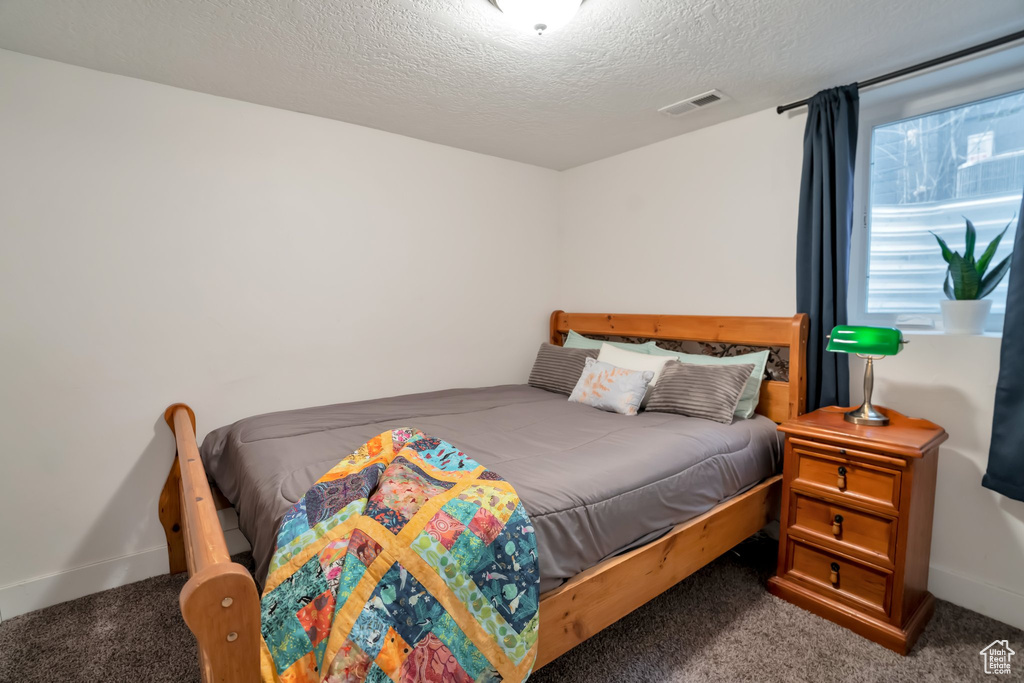 Carpeted bedroom featuring a textured ceiling, visible vents, and baseboards
