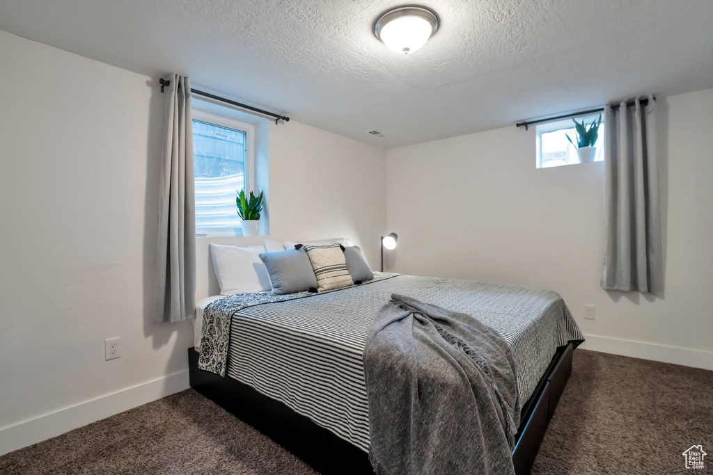 Bedroom featuring dark carpet, a textured ceiling, and baseboards