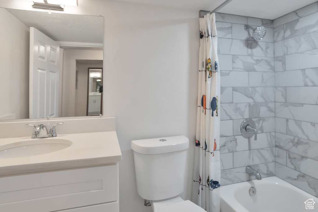 Bathroom with shower / bath combination with curtain, toilet, and vanity