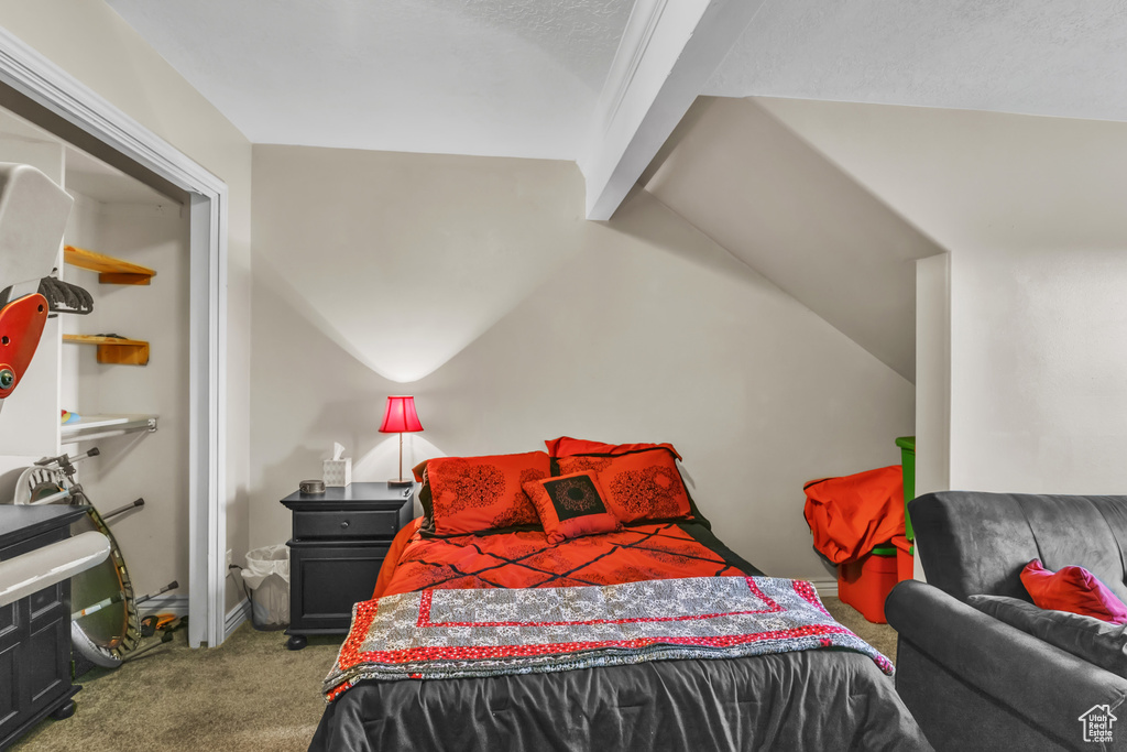 Bedroom with vaulted ceiling with beams and carpet