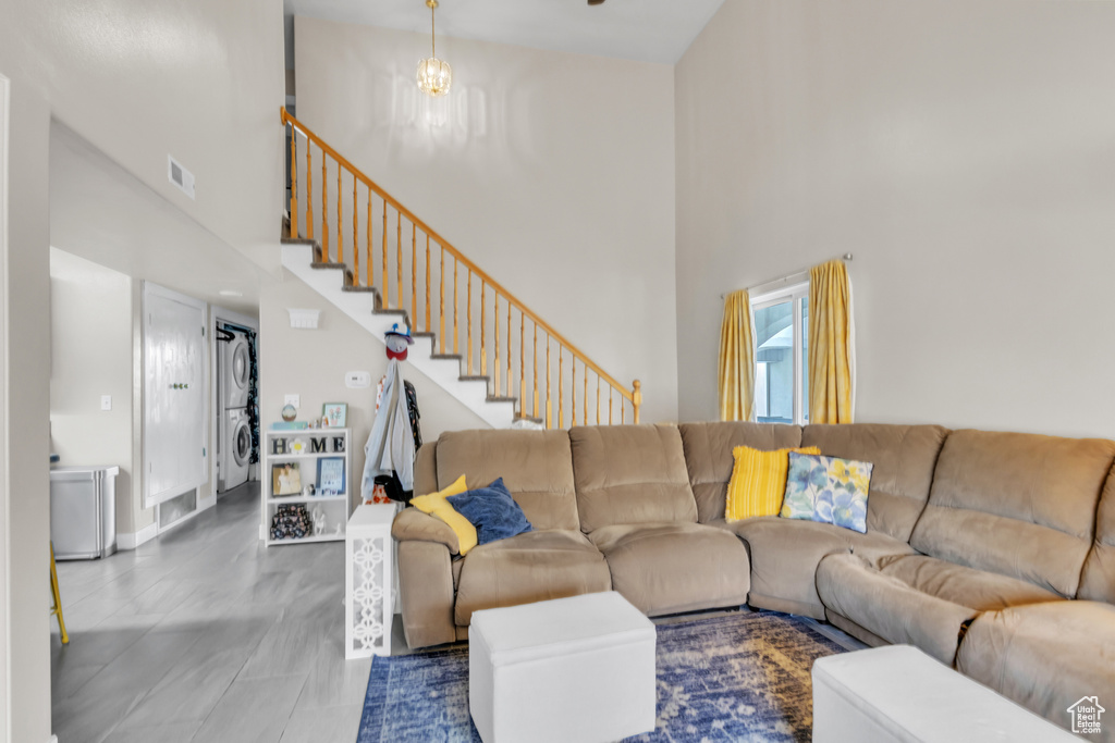 Living area featuring stairway, stacked washer / drying machine, a towering ceiling, and visible vents