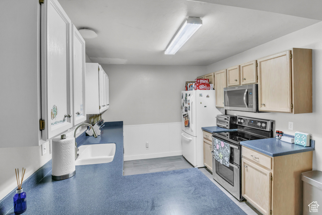 Kitchen with a sink, stainless steel appliances, light brown cabinets, a toaster, and dark countertops