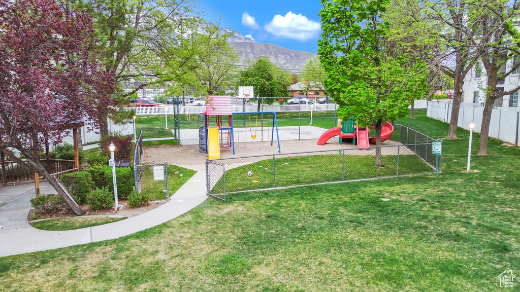 Community playground with a mountain view, a lawn, and fence