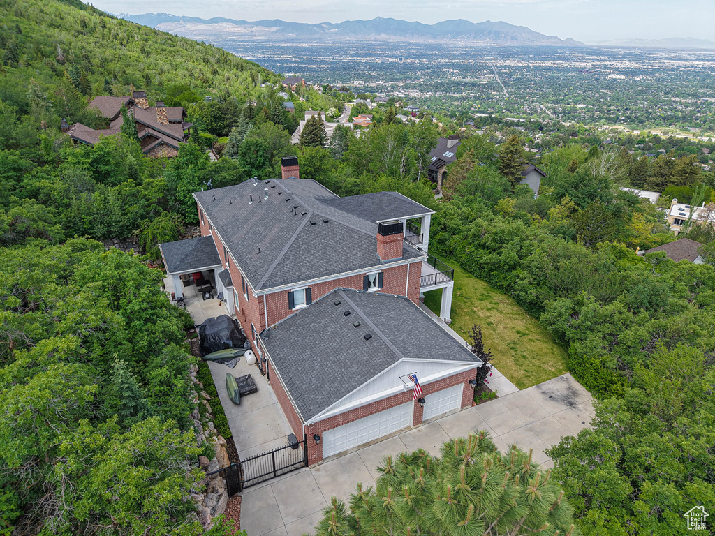 Aerial view of property and surrounding area featuring mountains and a heavily wooded area