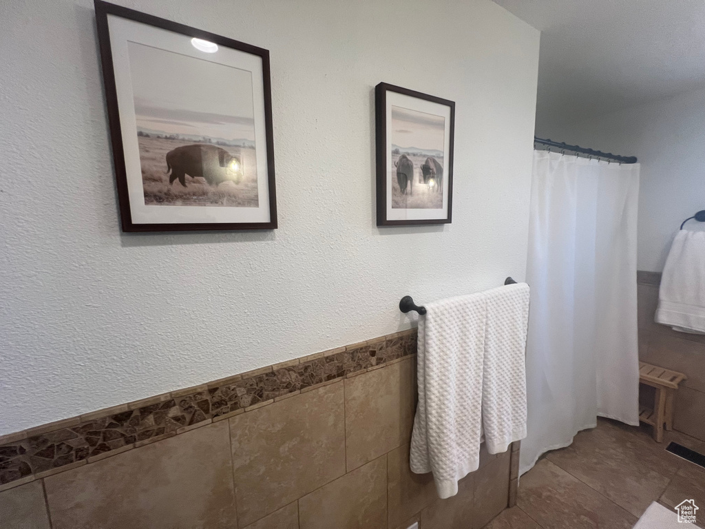 Full bath with tile walls, curtained shower, and tile patterned flooring
