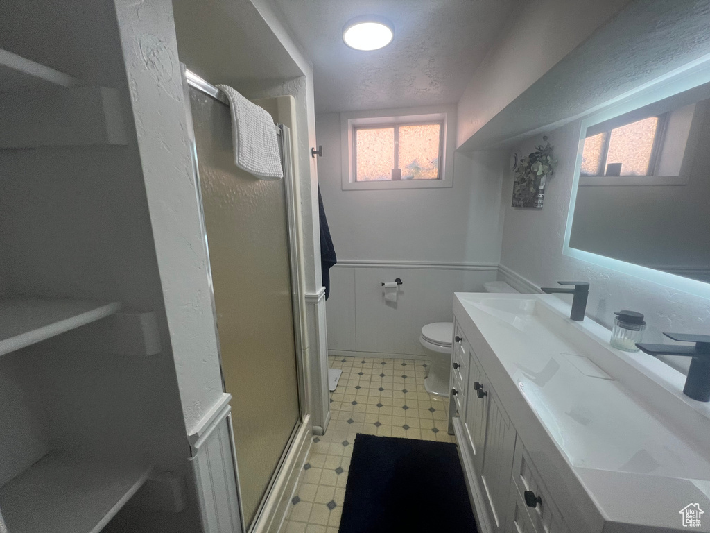 Bathroom with a shower stall, vanity, tile patterned floors, toilet, and a textured ceiling