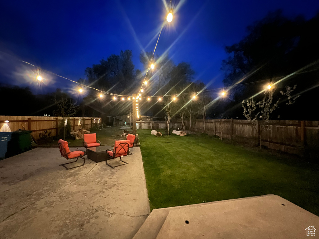 Yard at night with a patio and a fenced backyard