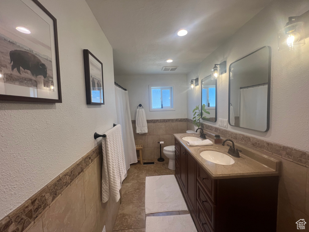 Full bathroom featuring a sink, visible vents, toilet, tile walls, and tile patterned flooring