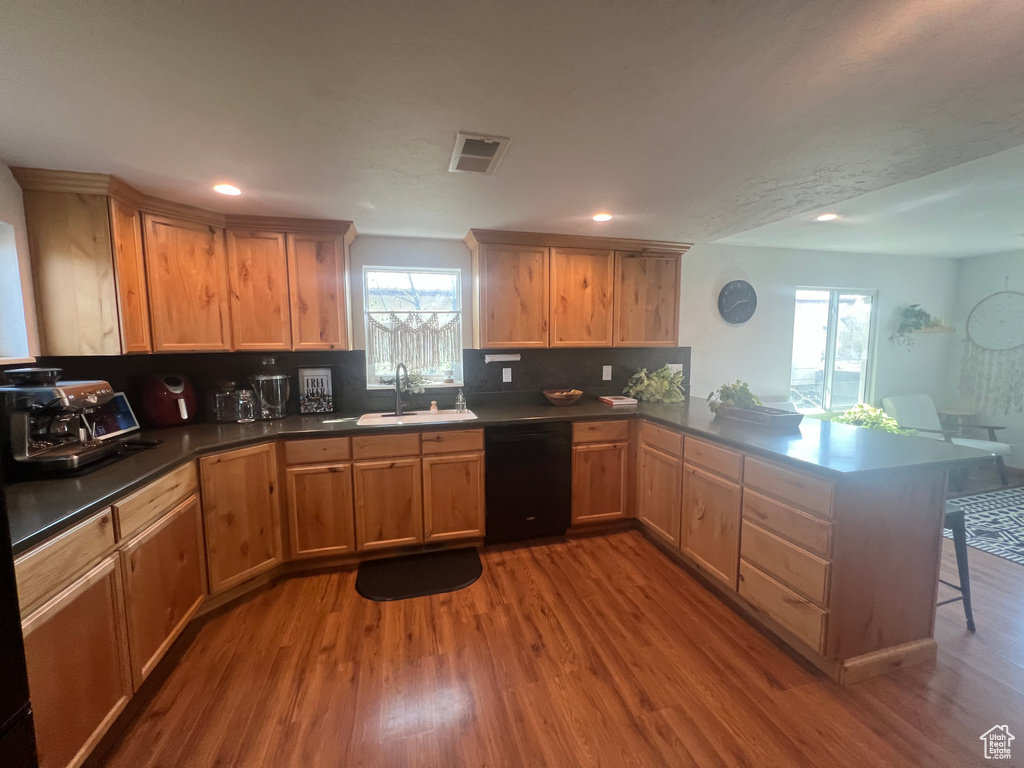 Kitchen featuring a sink, visible vents, black dishwasher, wood finished floors, and a peninsula