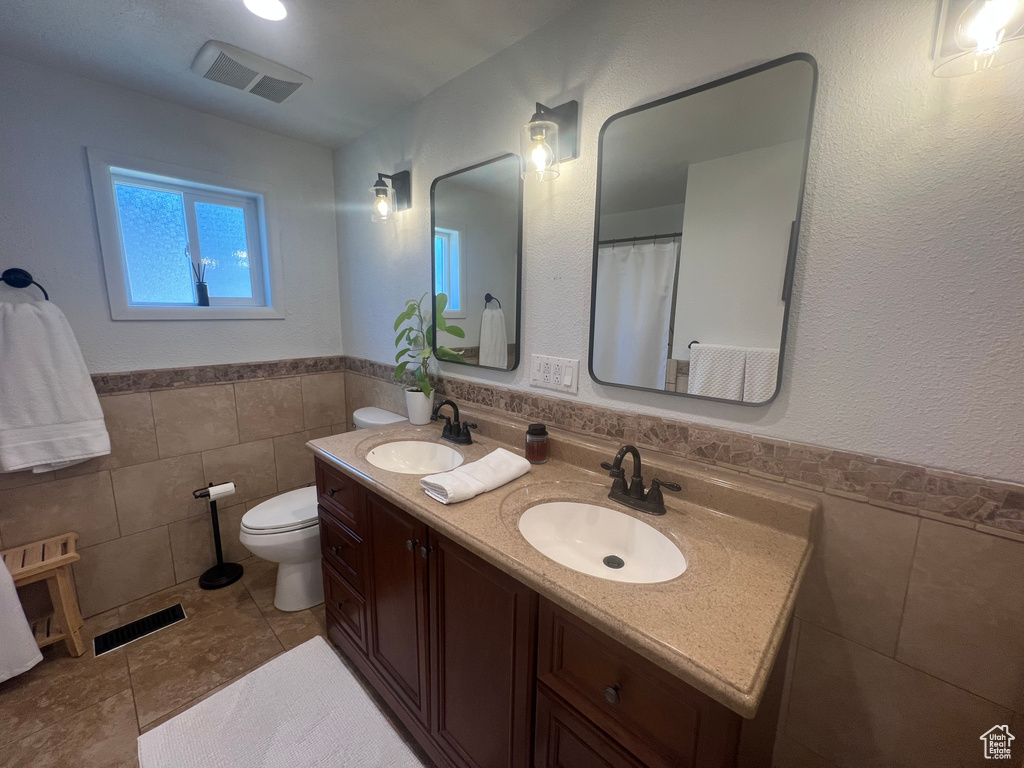 Bathroom with tile walls, a sink, and visible vents