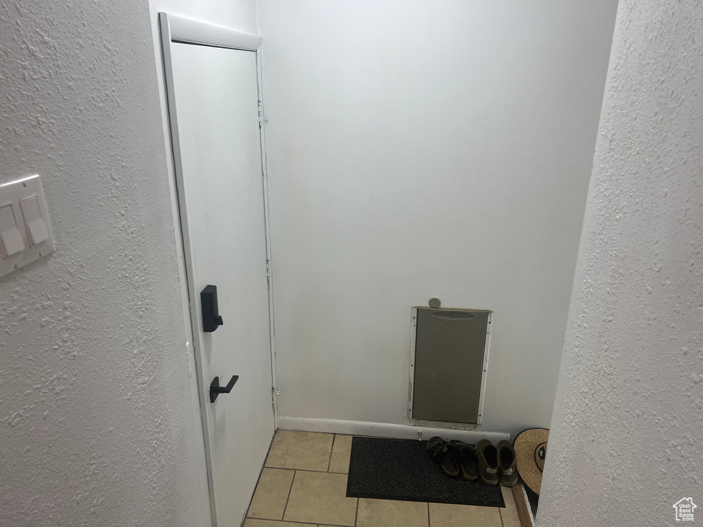 Washroom featuring light tile patterned floors and a textured wall