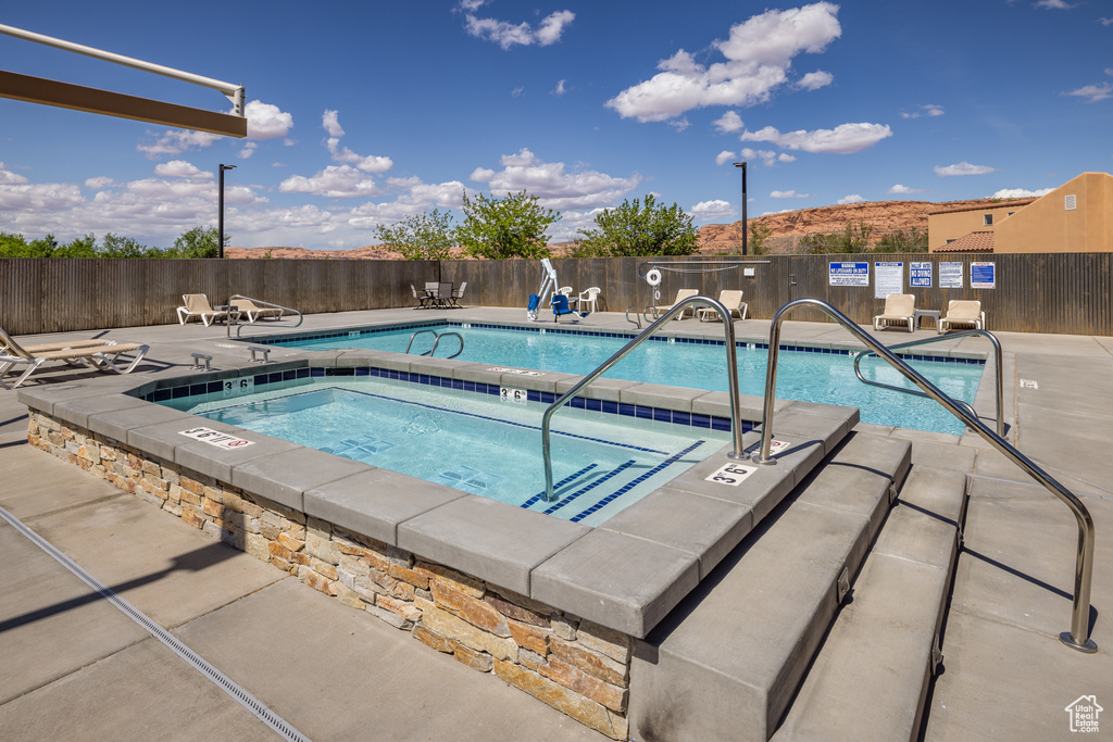 Pool featuring a community hot tub and fence