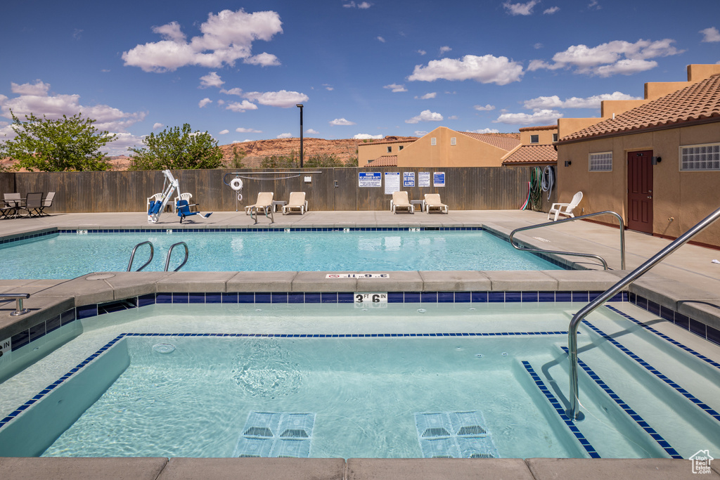 Community pool featuring a community hot tub, a patio area, and fence