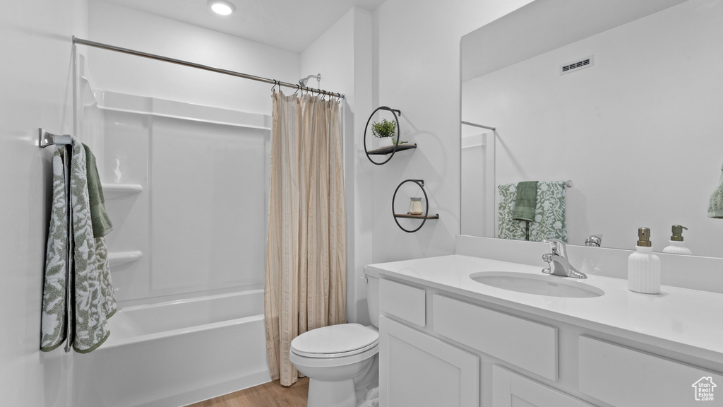 Full bathroom featuring wood finished floors, shower / bathtub combination with curtain, toilet, vanity, and visible vents