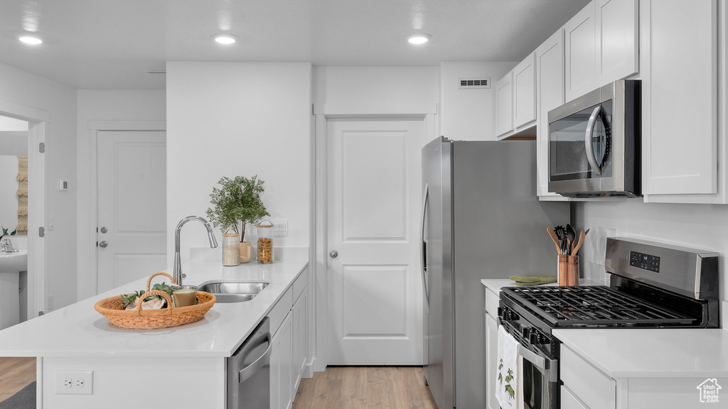 Kitchen with stainless steel appliances, light countertops, a sink, visible vents, and a peninsula