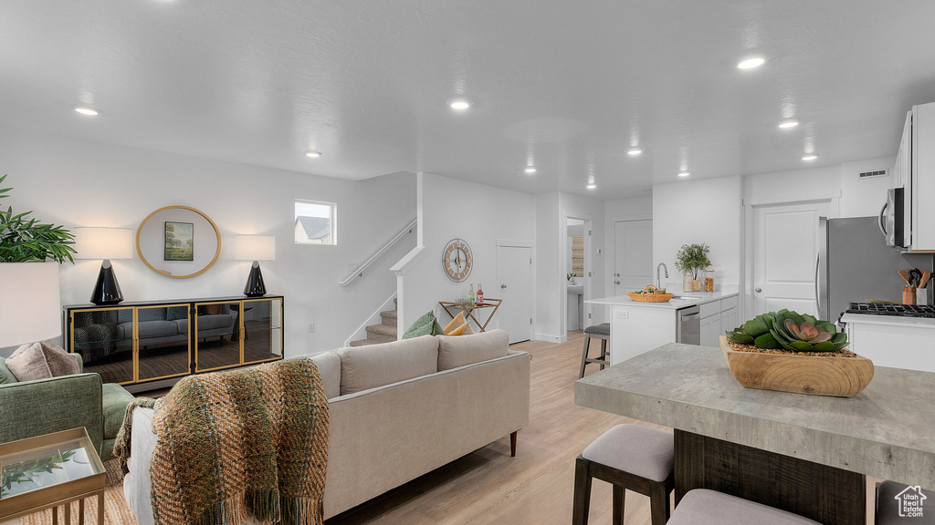 Living room featuring light wood finished floors, recessed lighting, and stairway