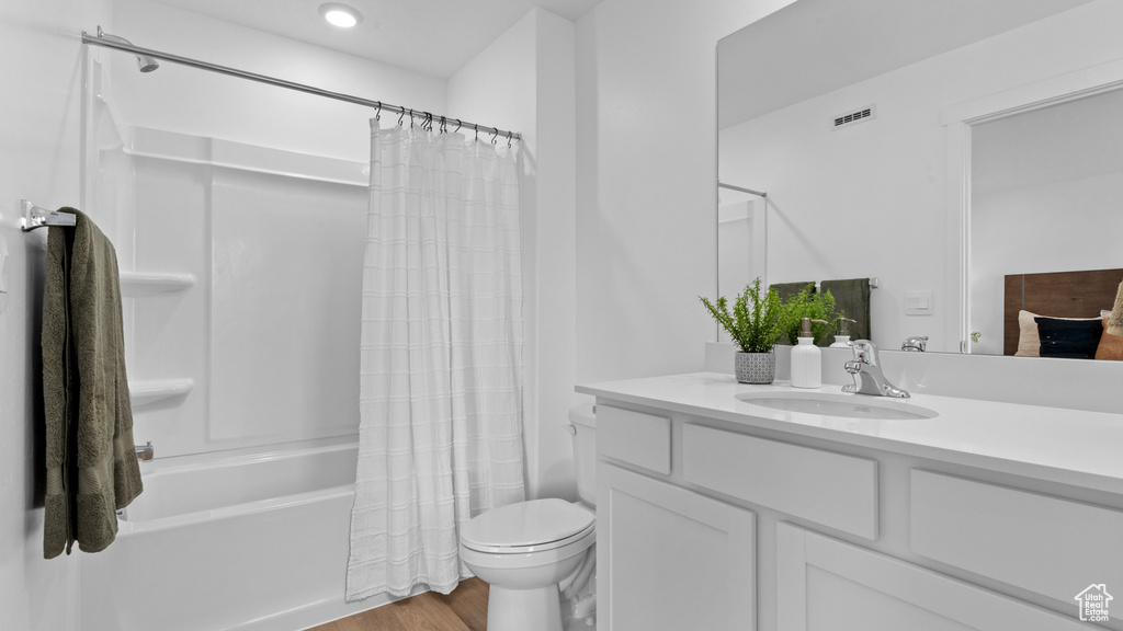 Full bathroom featuring vanity, shower / bath combination with curtain, toilet, visible vents, and wood finished floors