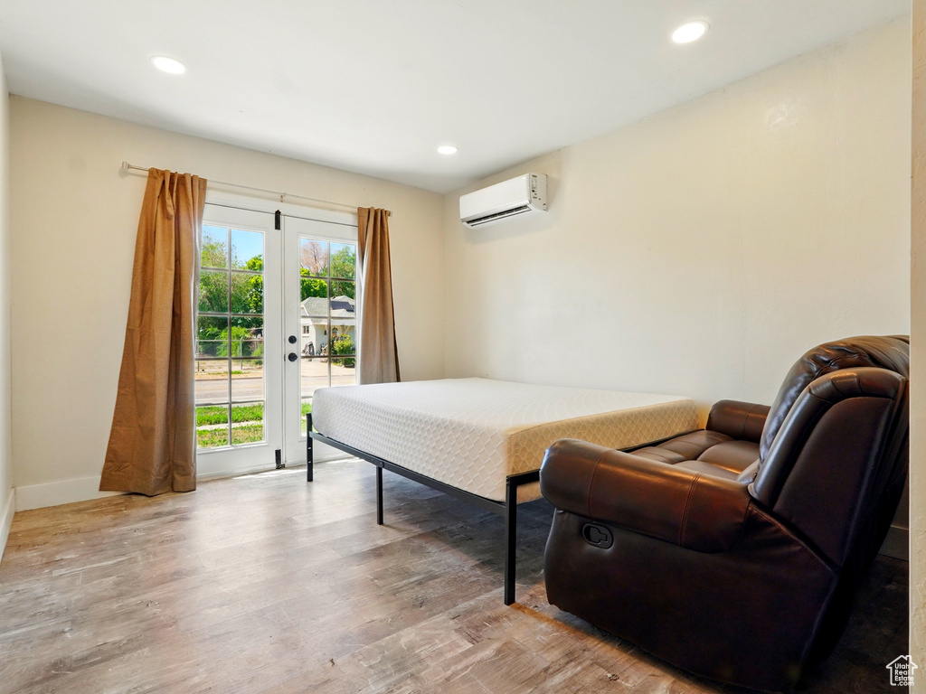 Bedroom featuring a wall mounted AC, access to exterior, wood finished floors, baseboards, and recessed lighting