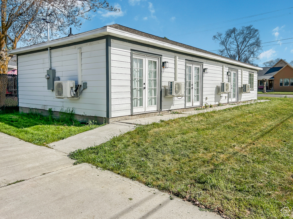 View of side of home featuring a lawn, french doors, and ac unit