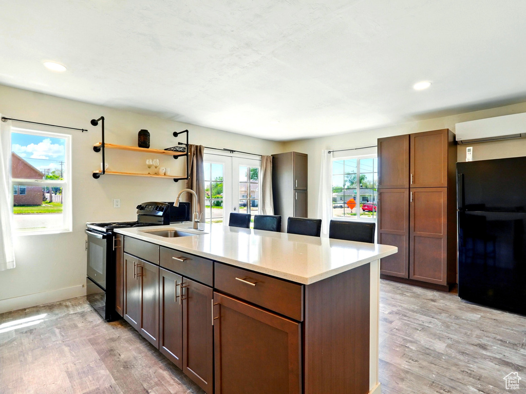 Kitchen with a sink, black appliances, light wood finished floors, light countertops, and recessed lighting