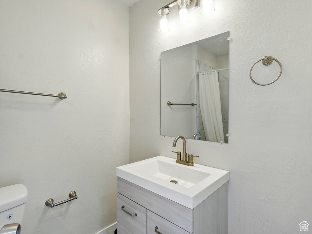 Full bath with toilet, vanity, and a shower with shower curtain