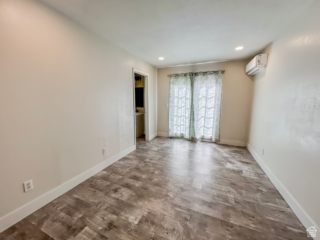 Unfurnished bedroom with baseboards, a wall mounted air conditioner, wood finished floors, and recessed lighting