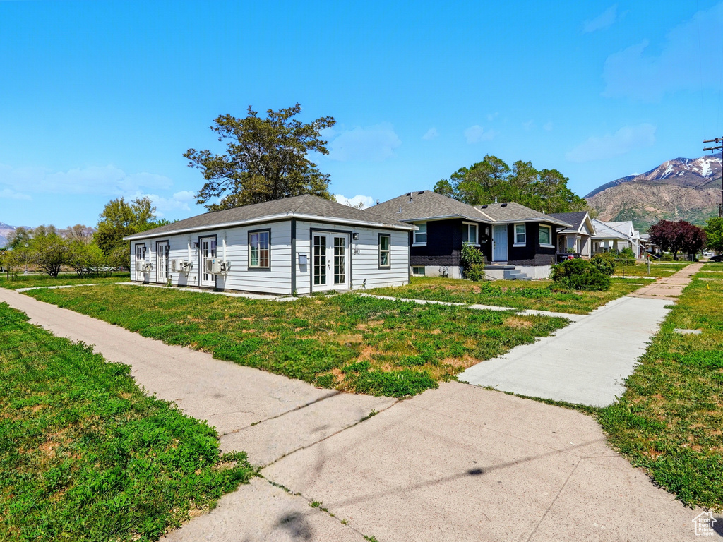 View of front of house with french doors, a front yard, and a mountain view